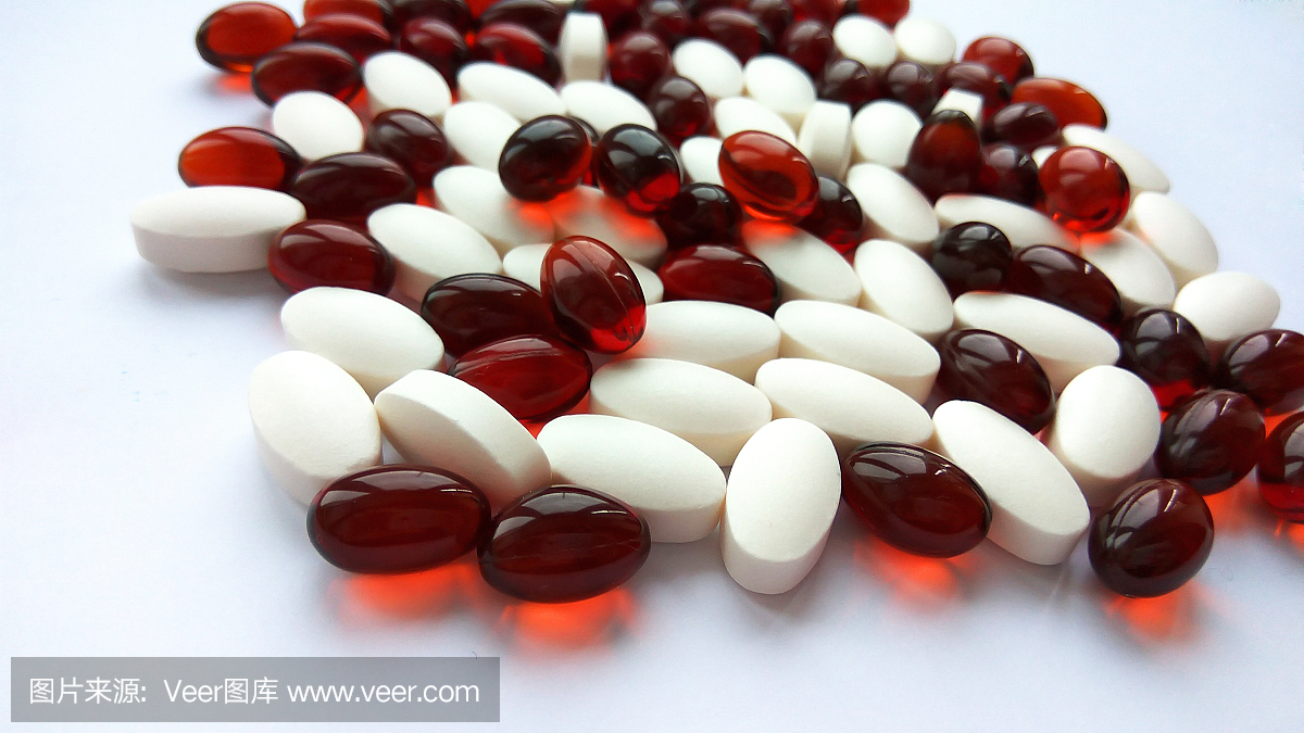 近看红色和白色的彩色药物药丸和胶囊在白色的背景